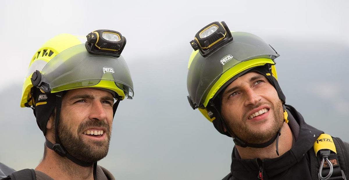 Twee technici met gele Petzl Vertex Vent Hi-Viz-helmen met vizier en hoofdlamp